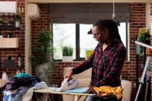 African american woman ironing clothes at home.