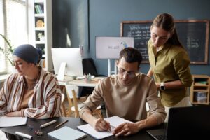 Diverse Group of Adult Students Writing Test Sitting at Desk in English Class