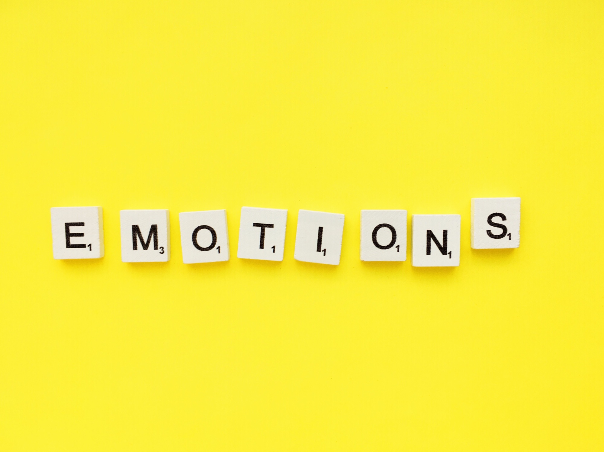 Emotions scrabble letters word on a yellow background