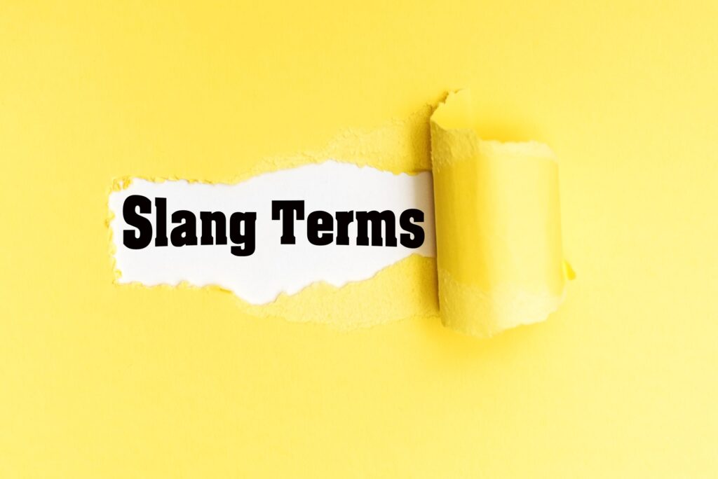 English phrase Slang Terms written on torn yellow paper.
