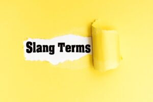 English phrase Slang Terms written on torn yellow paper.