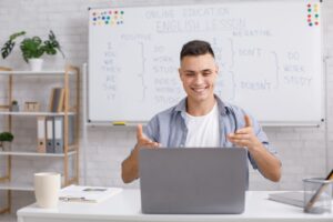 English teacher at home, online practice during COVID-19. Smiling young man rejoices at students
