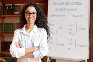 English teacher standing at board, posing at camera