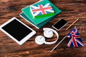 gadgets near books and copybooks and uk flags on wooden table