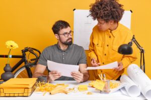 Indoor shot of skilled students analyze exam mistakes pose at office desk do homework in coworking s