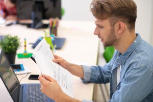 Male teacher sitting at laptop, checking grammar test