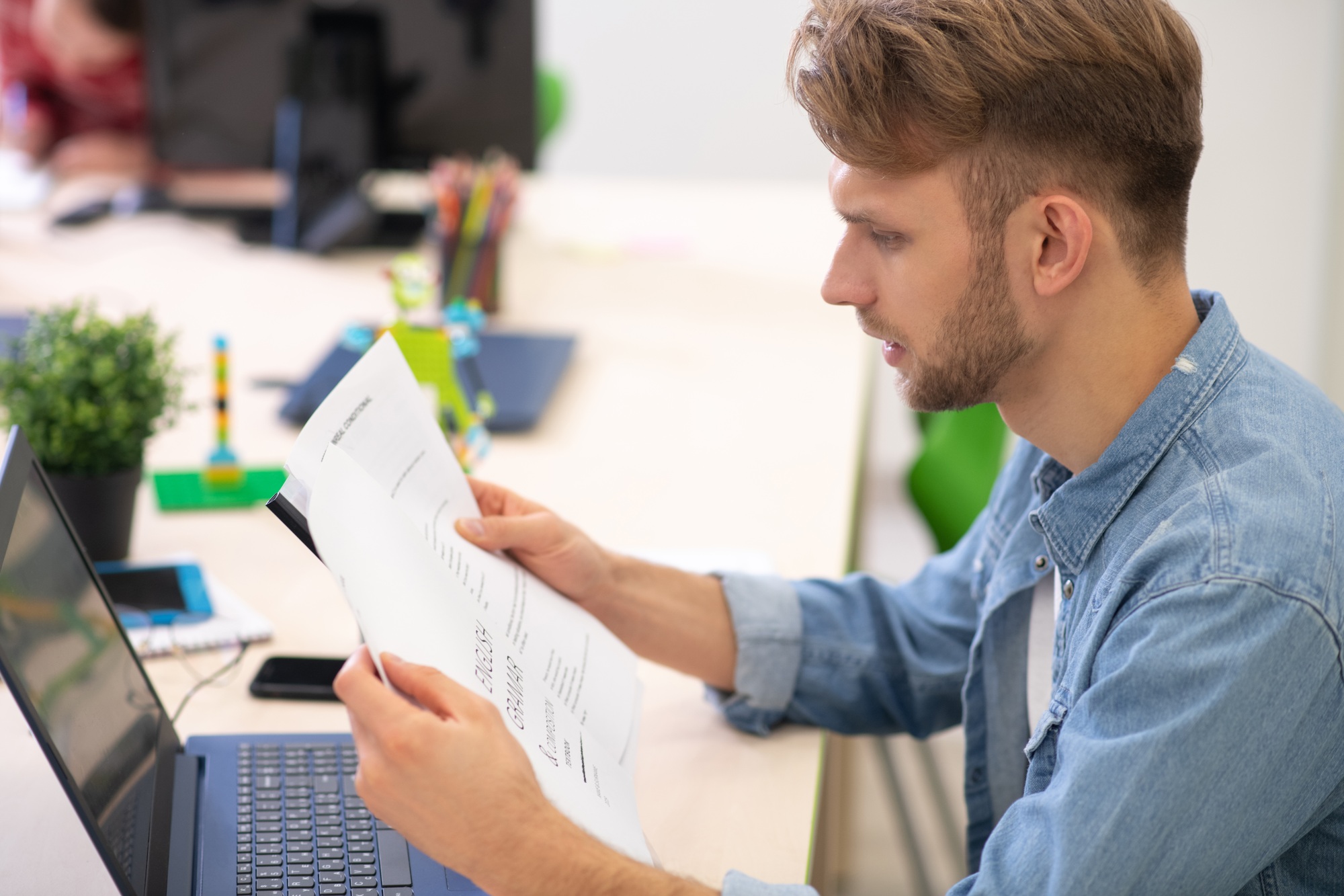 Male teacher sitting at laptop, checking grammar test
