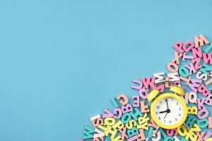 Many multicolored letters and alarm clock. Back To School. School studies, teaching to read.