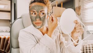 One pretty adult young woman busy in daily skin face care routine using natural green mask