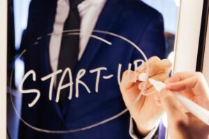 Smart business man writing the word Start-up on the mirror board
