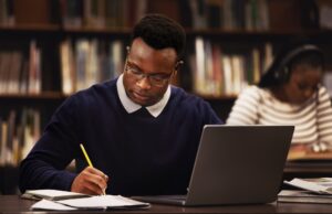 Student, man and writing in library for studying, research and planning in university, scholarship