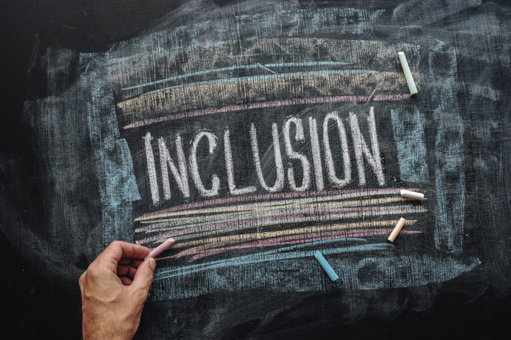 Teacher writing word Inclusion on school blackboard, inclusive e