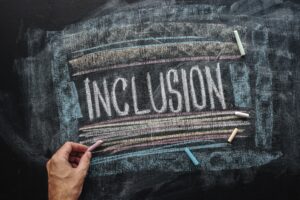 Teacher writing word Inclusion on school blackboard, inclusive e