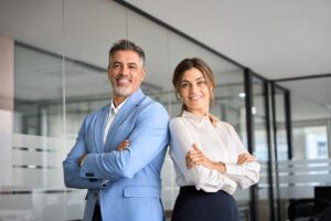 Two happy executives business man and woman standing arms crossed in office.