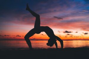 Woman in Inverted Staff Pose on beach at sunset