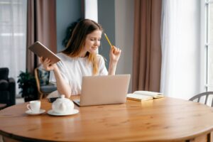 Woman studying online at home on the school website. Writes an email message.