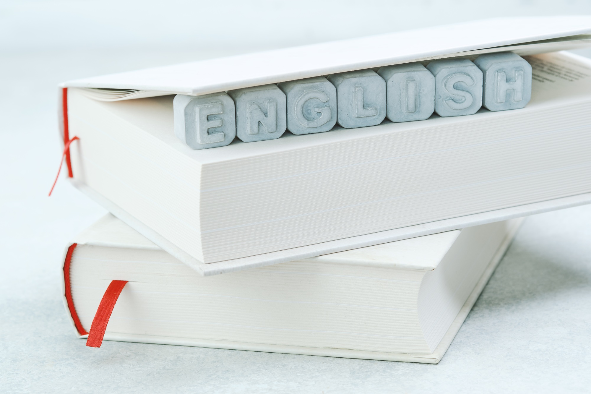 Word English made from gray concrete letters on a white book. English language studying