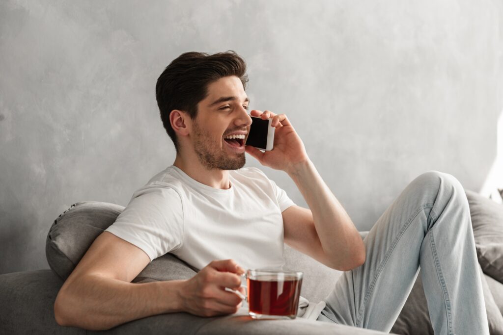Young and beautiful man in basic t-shirt smiling and speaking on