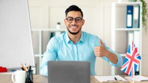 Young Arab tutor conducting online English lesson, showing thumb up, teaching foreign language from