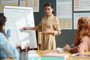 Young confident woman explaining new grammar rules to pupils