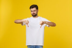 Young handsome man wearing white t-shirt over isolated background Doing thumbs down, disagreement