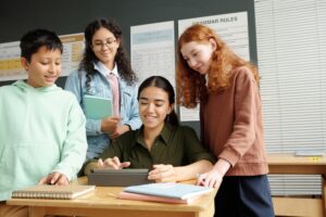 Young smiling teacher scrolling through online information on tablet screen