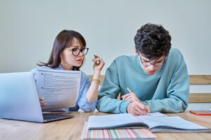 Young teenage male studying languages with teacher in classroom