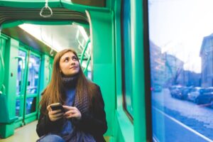 young woman outdoor using smart phone travelling transport